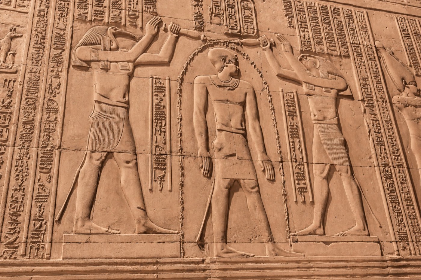 Ancient Egyptian temple wall relief, priests performing an initiation ritual in golden light